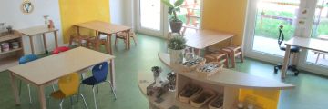 Das Gelbe Zimmer mit Tischen, Stühlen und Regalen